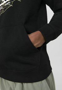Sudadera negra con bolsillo canguro, puños y dobladillo acanalados; presenta un diseño gráfico en blanco y amarillo en la parte delantera.