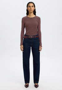 Langermet skjorte i maroon og hvite striper, kombinert med høytlivs mørkeblå denimjeans og et mørkerødt belte med sirkulær spenne.