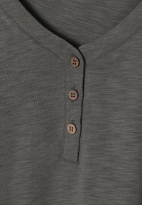 Grau strukturiertes Henley-Shirt mit V-Ausschnitt, ausgestattet mit drei braunen Holzknöpfen entlang der Knopfleiste.