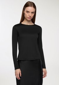 Czarna bluzka z długim rękawem i okrągłym dekoltem, wykonana z gładkiego materiału. Projekt charakteryzuje się dopasowaną sylwetką i sięga do bioder.