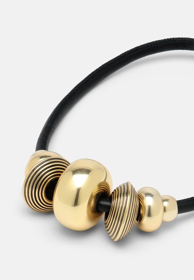 Guldtonede perler med varierende former og teksturer på et sort snor. Har glatte, ribbede og spiralformede designs for visuel kontrast.