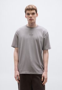 Szürke pamut rövid ujjú póló, kerek nyakkivágással és finom "BOSS" hímzéssel a mellkasnál. Puha tapintású és laza szabású.