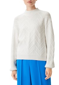 Weißer Strickpullover mit strukturiertem Fischgrätmuster, hohem Kragen und überschnittenen Schultern, kombiniert mit einem hellblauen Rock.