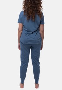 Sininen puuvillainen loungemekko, jossa on lyhyet hihat ja kapeat housut nilkkakuvioilla. Sujuva pinta ja rento istuvuus.