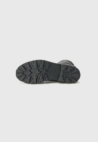 Suela de bota negra con patrón de agarre texturizado, con el nombre de la marca "BOGNER". Colocada sobre un fondo blanco liso.