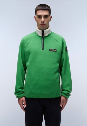 Grüner Fleece-Pullover mit weißem Kragen, halblanger Reißverschlussvorn und schwarzem Logo-Patch. Mit Raglanärmeln und einer strukturierten Stoffoberfläche.