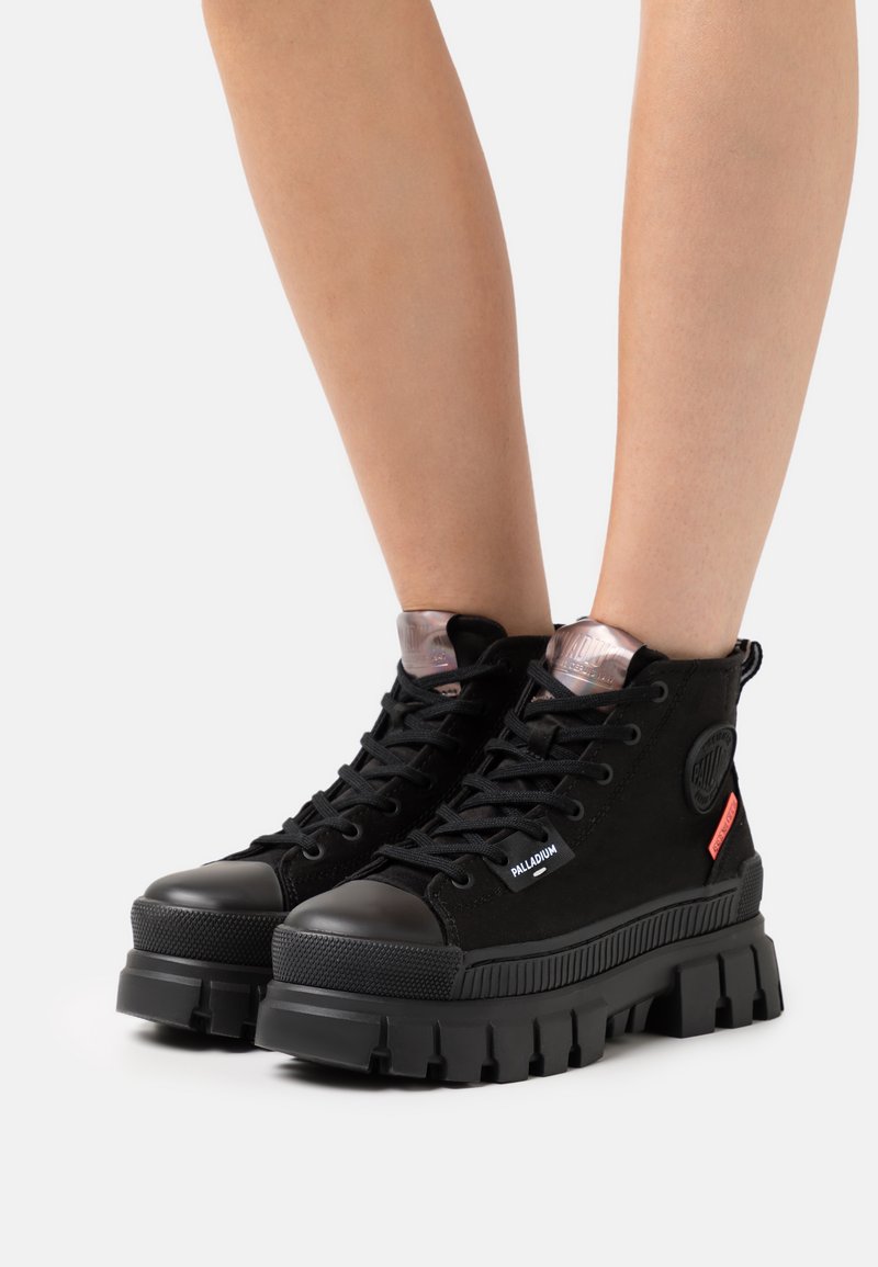 Bottines en toile noire avec un capuchon en caoutchouc et une semelle épaisse. Accents transparents au col et patch logo sur le côté. Design à lacets.