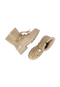 Bottines en daim beige avec une semelle en caoutchouc épaisse, une fermeture à lacets, un col rembourré et une doublure intérieure douce. Comprend des accents argentés et une finition texturée.