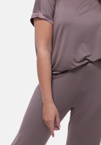 Ljus mauve loungewear-set som har en lös passform med kort ärm och smalt skurna byxor, tillverkat av mjukt, slätt tyg med matt yta.