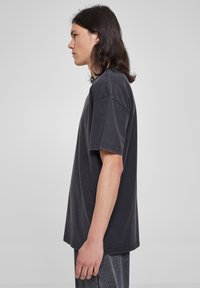 Tricou supradimensionat de culoare gri închis, cu mâneci scurt, din material de bumbac moale, cu cusături vizibile și tiv drept.