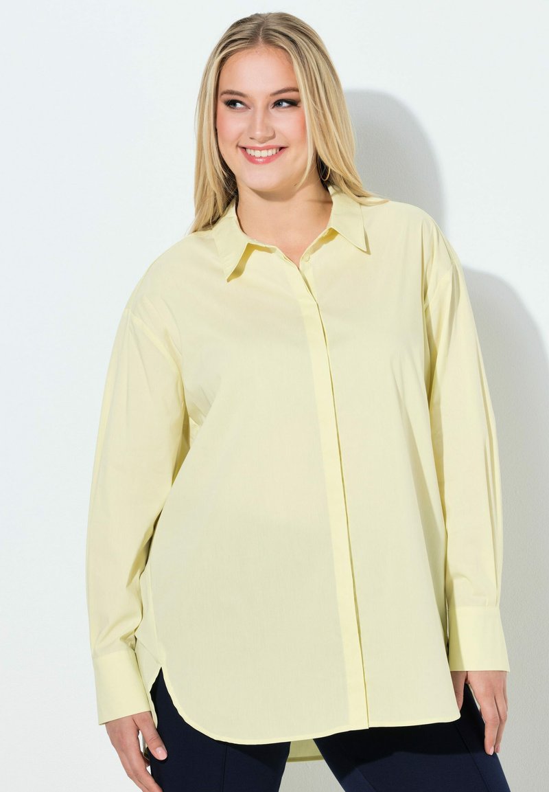Camicia giallo chiaro a maniche lunghe con bottoni, scollo con colletto e orlo arrotondato. Tessuto liscio con vestibilità comoda e polsini aderenti.