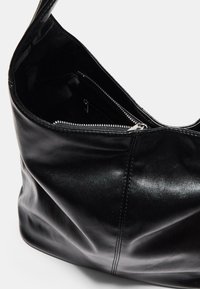 Borsa a spalla in pelle nera con una texture liscia, tasca con zip e un ampio interno. Presenta dettagli di cucitura sottili.