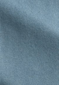 Jasnoniebieski denim o gładkiej fakturze, z klasycznym wzorem tkania skośnego. Powierzchnia pokazuje delikatne zróżnicowania i głębię.