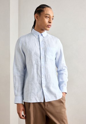 Lichtblauwe overhemd met lange mouwen van textuurstof, met een borstzak en witte knopen, gecombineerd met een bruine broek.