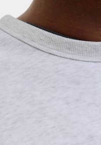 Lichtgrijze katoenen sweatshirt met een gestructureerde ribgebreide kraag. Close-up weergave die de gladde stof en subtiele kleurvariaties toont.