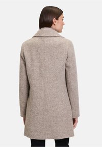 Beige wollen jas met een gelapte kraag, details in de rugnaad en een middenlange snit. Gladde textuur geschikt voor zowel casual als formele gelegenheden.
