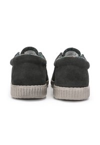 Chaussures en daim gris foncé avec un dos arrondi, semelle en caoutchouc gris texturé et col rembourré. Détails de couture minimalistes le long des coutures.