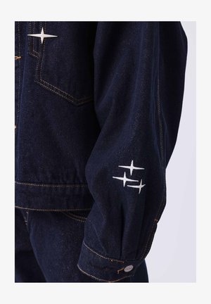 Dunkelblaue Jeansjacke mit strukturiertem Design, ausgestattet mit weißen Sternstickereien auf dem Ärmel und kontrastierenden gelben Nähten.
