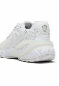 Sneaker atletico bianco con materiali in rete e sintetici, dettagli testurizzati, collo imbottito e design della suola curvata per supporto.