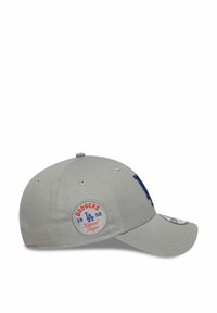 Gorra de béisbol gris con visera curvada, que presenta un logo bordado azul "LA" y un parche circular de los Dodgers con detalles en rojo, azul y blanco.