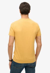 Kortærmet gul t-shirt lavet af blødt stof. Standard crew neck design med en afslappet pasform og minimale sømme bagpå.