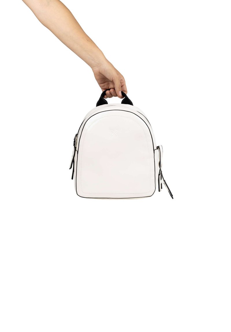 Mochila de cuero blanca con un diseño redondeado, acentos en negro, cremalleras dobles y un asa superior, representada en una posición sostenida a mano.