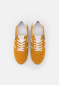 Orange suede sneakers with white accents, featuring perforated details, a white lace system, and a side zipper for easy wear.