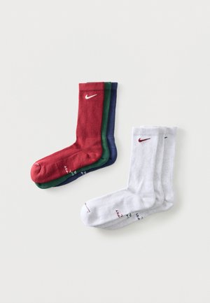 Tre par Nike crew-sokker stablet i rødt, grønt og blåt til venstre; tre par hvide Nike crew-sokker til højre, alle på hvid baggrund.