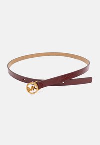 Slanke donkerrode leren riem met een gouden ronde gesp met daarin de onderling verwoven "MK" initialen op een witte achtergrond.