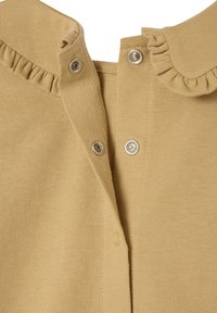 Mustard yellow top with a rounded collar and ruffled edge. Features silver snap buttons along the front and a soft, textured fabric.