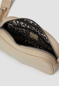 Borsa in pelle beige con chiusura a zip, dotata di una fodera con stampa leopardata e due tasche interne. Texture liscia e forma arrotondata.