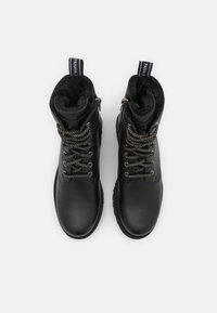 Bottes de cheville en cuir noir avec un col en fourrure, lacets gris et noirs à motif, et un design de languette à boucle pour un enfilage facile.