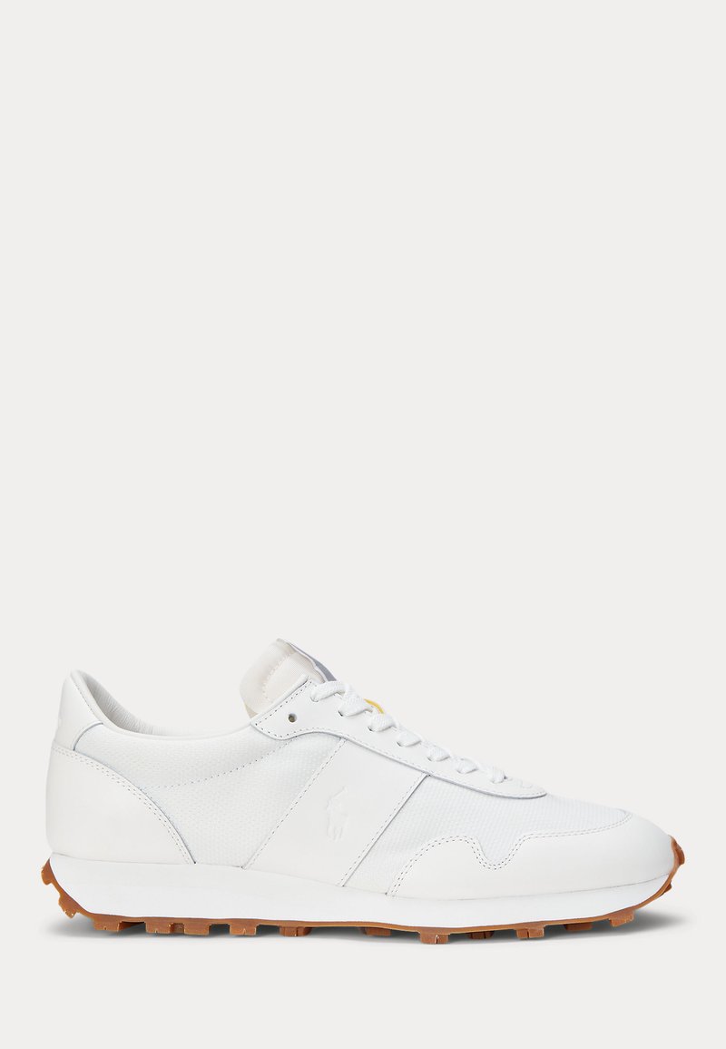 Zijaanzicht van een witte lage sneaker met witte veters en een bruine rubberen zool.