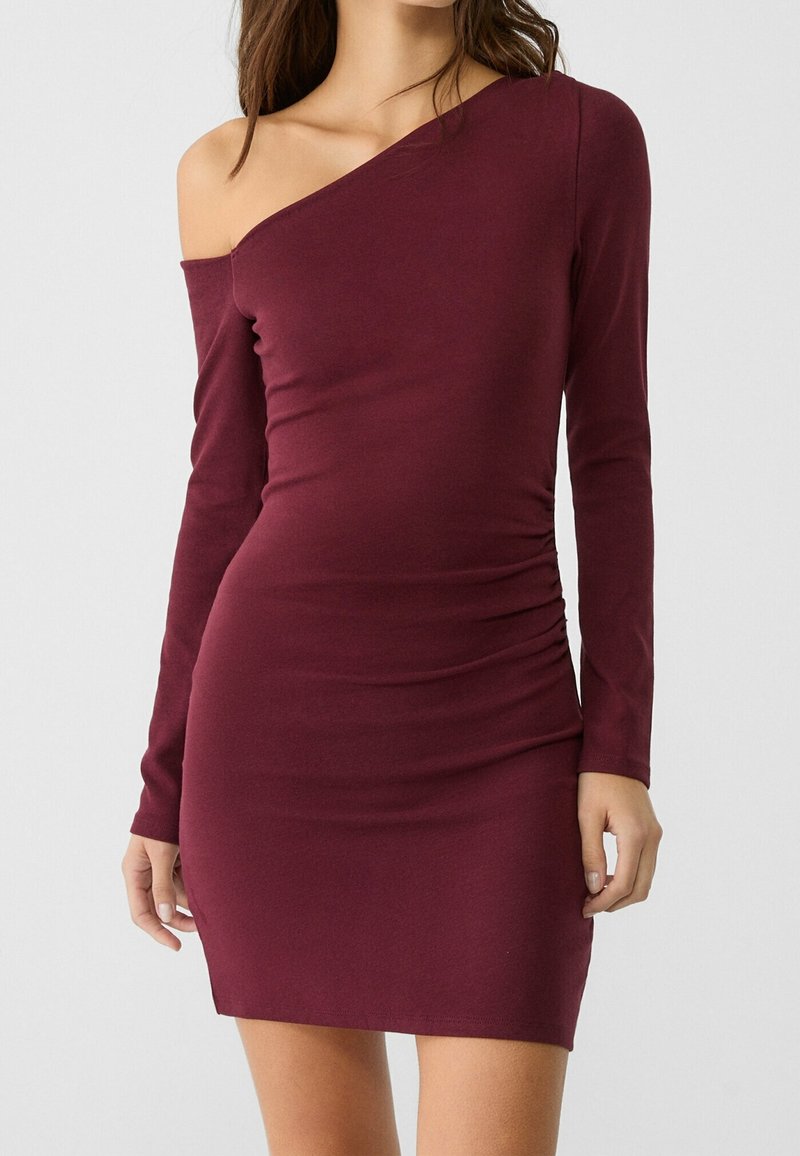 Robe bordeaux à épaules dénudées en tissu doux avec manches longues, coupe ajustée et détails froncés sur le côté. Idéale pour des occasions décontractées ou semi-formelles.