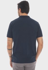 Polo shirt blu navy realizzato in cotone, con colletto classico, maniche corte e orlo dritto, senza loghi o motivi visibili.