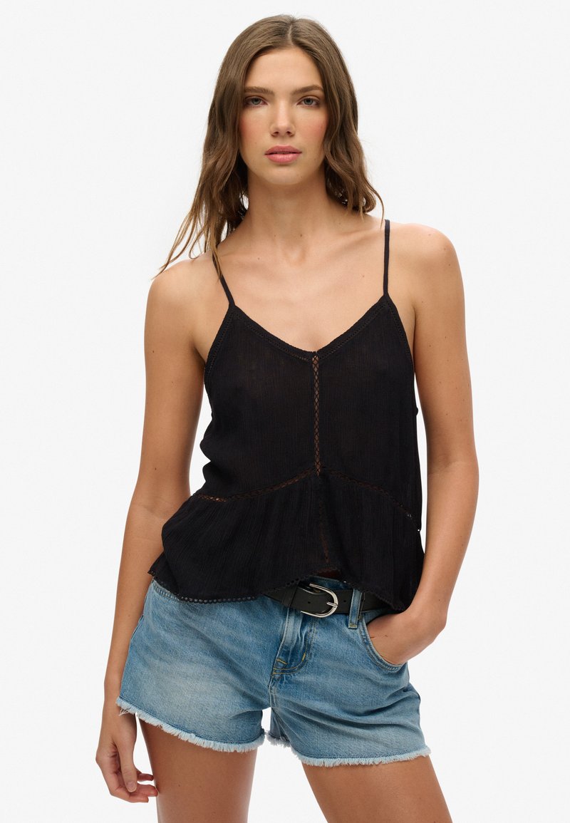 Zwarte camisole met dunne bandjes, textuurstof, uitlopende zoom, met contrasterende stikdetails, gecombineerd met lichtblauwe denim shorts.