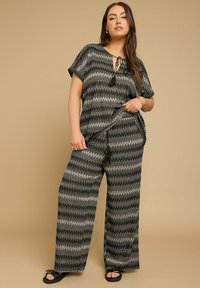 Set a due pezzi a zigzag nero e grigio con maniche corte e pantaloni a gamba larga, caratterizzato da un colletto annodato e vestibilità ampia.