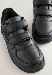 Chaussures noires en synthétique avec deux bandes Velcro ajustables, bout rond et semelle en caoutchouc texturé. Présente des détails cousus et une doublure confortable.