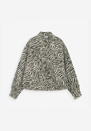 Chemise à manches longues avec boutons, à rayures zèbre noires et blanches, avec deux poches poitrine à boutons à l'avant.