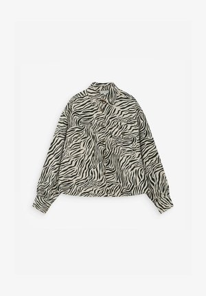 Chemise à manches longues avec boutons, à rayures zèbre noires et blanches, avec deux poches poitrine à boutons à l'avant.