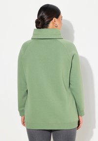 Felpa verde in cotone misto con colletto alto, maniche raglan e spacchi laterali all'orlo. Presenta una texture liscia e una vestibilità rilassata.