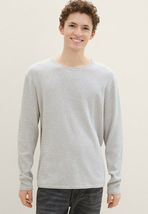 Gray long-sleeve t-shirt with a textured pattern, crew neckline, and ribbed cuffs, paired with dark jeans. Clean, simple design and fit.