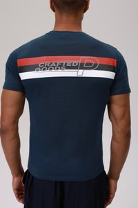 Camiseta azul marino de cuello redondo; presenta un diseño de rayas gráficas en rojo, negro y blanco con el texto "PRODUCTOS CREADOS" en la parte posterior.