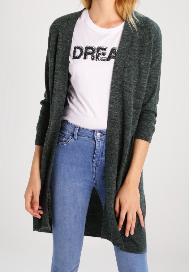 Femme portant un cardigan gris foncé ouvert sur un t-shirt blanc avec le texte "DREAM" et un jean taille haute bleu clair.