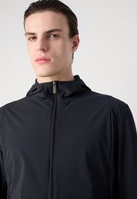 Black lightweight zip-up jacket with a hood, featuring a smooth texture and minimalistic design. Zipper closure at the front.