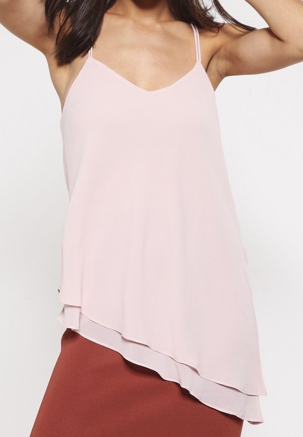 Blouse sans manches rose clair avec un profond col en V et un bas à volants superposés. Fabriquée en tissu lisse avec des bretelles fines réglables.