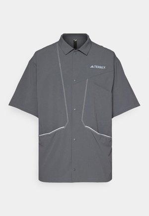 Szara koszula z krótkim rękawem z kołnierzykiem, przednimi guzikami, dwiema kieszeniami z białymi szwami oraz logo "TERREX" na górnej lewej stronie.