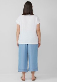 Witte katoenen t-shirt met korte mouwen, gecombineerd met lichtblauwe wijde denimbroek met omgeslagen zoom en een soepele textuur.