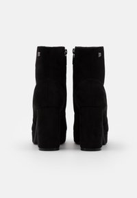 Bottes cheville en daim noir avec talon bloc, fermetures éclair latérales et design à bout rond, ornées de coutures ton sur ton discrètes et d'accents du logo de la marque.