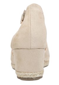 Scarpa con zeppa in suede beige con un'inserto di juta intrecciata lungo la suola, superficie liscia e tacco arrotondato. Dettagli delle cuciture visibili sul retro.